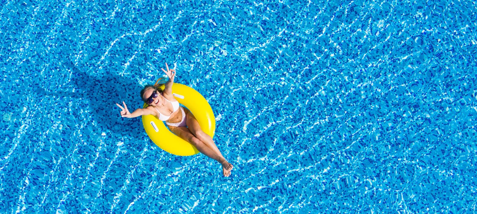Beautiful Woman In Swimming Pool Aerial Top View From Above. Young Girl In Bikini Relaxes And Swims On Inflatable Ring Donut And Has Fun In Water On Family Vacation, Tropical Holiday Resort